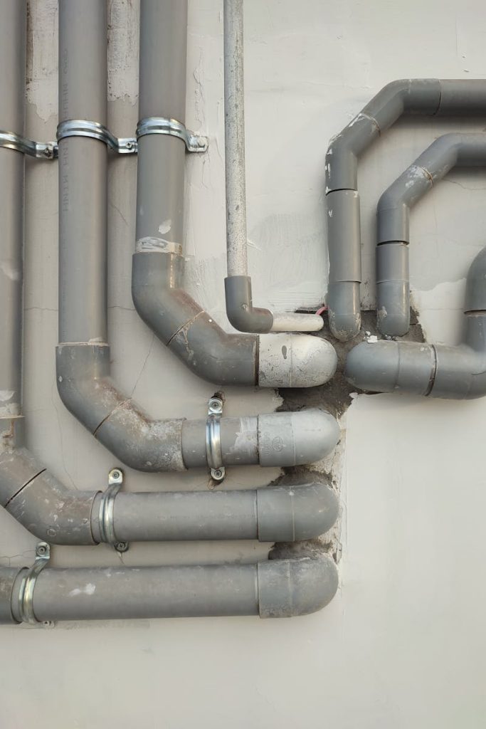 Close-up of interconnected gray metal pipes on an outdoor wall showcasing industrial design.