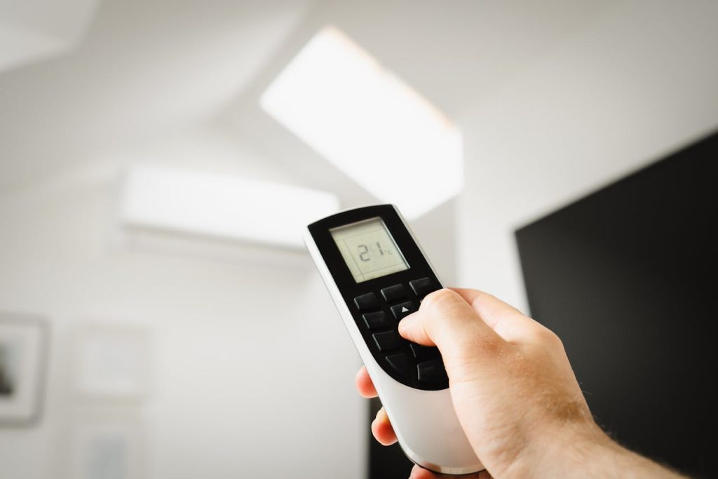 pexels-photo-16695385 Close-up of a man using a remote to control air conditioning indoors.